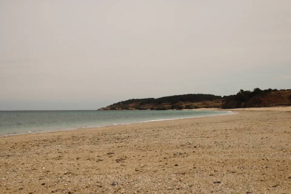 Plage de sable et de galets des Grands Sables bordée d'une pointe boisée
