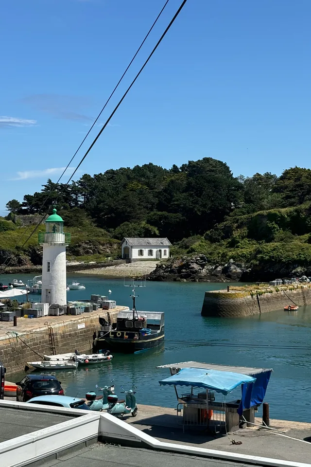 Phare vert à l'entrée du port de Sauzon et bateau de pêche amarré au quai